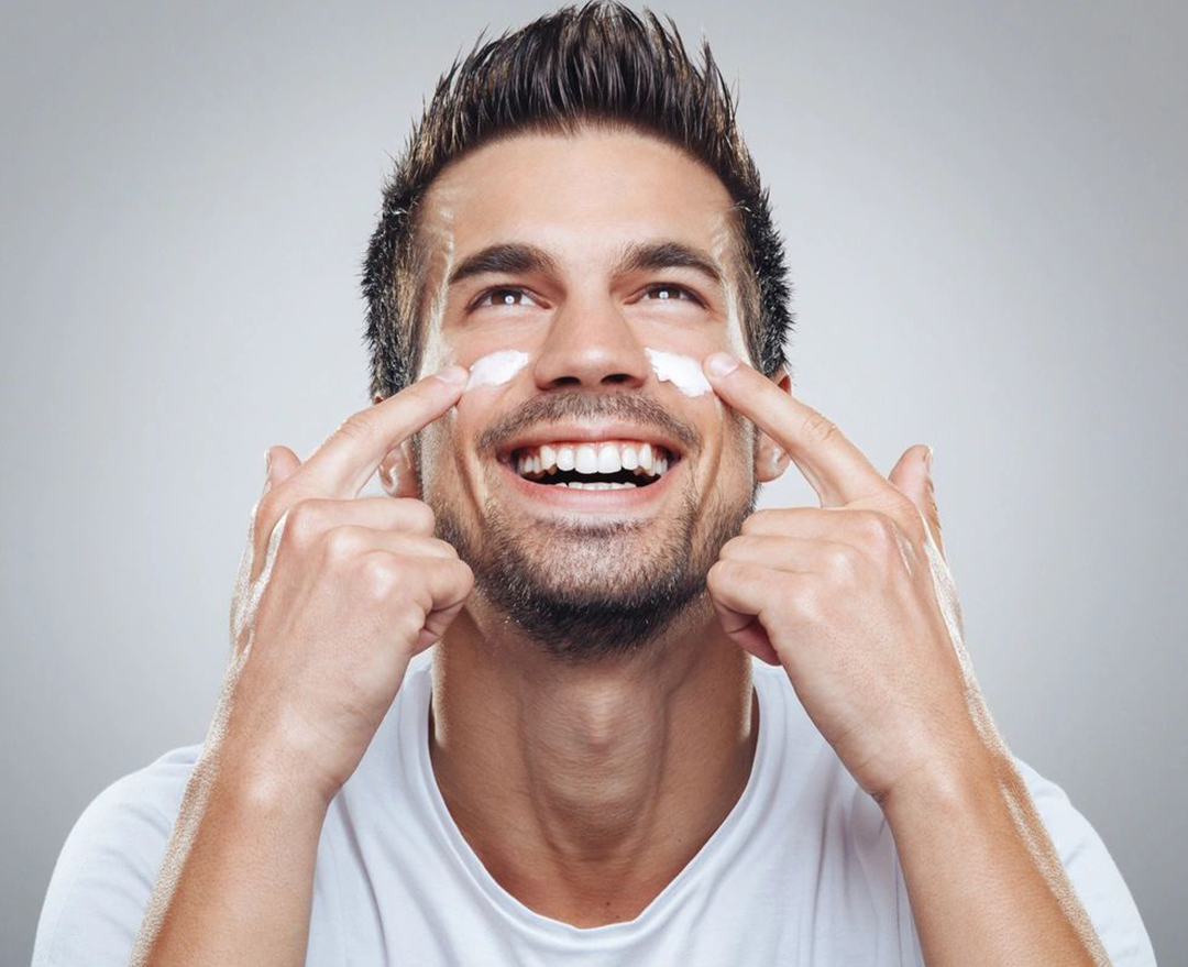 A man putting cream on his face.