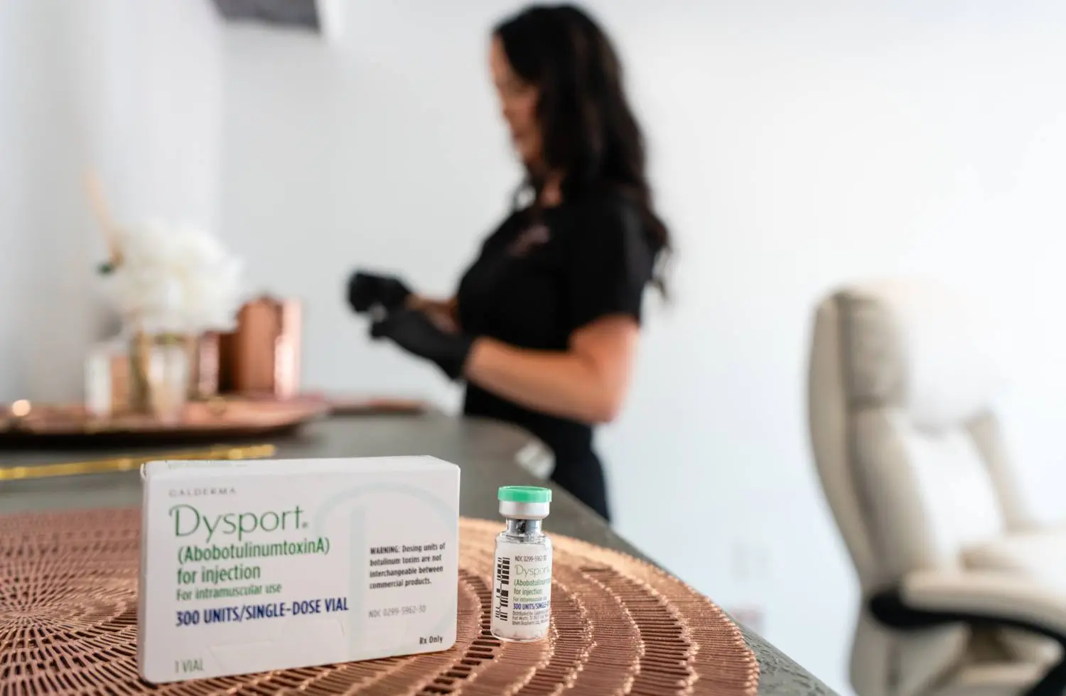 A woman standing at the table with a bottle of medicine.